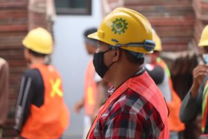 operaio con elmetto giallo e giubbetto catarifrangente